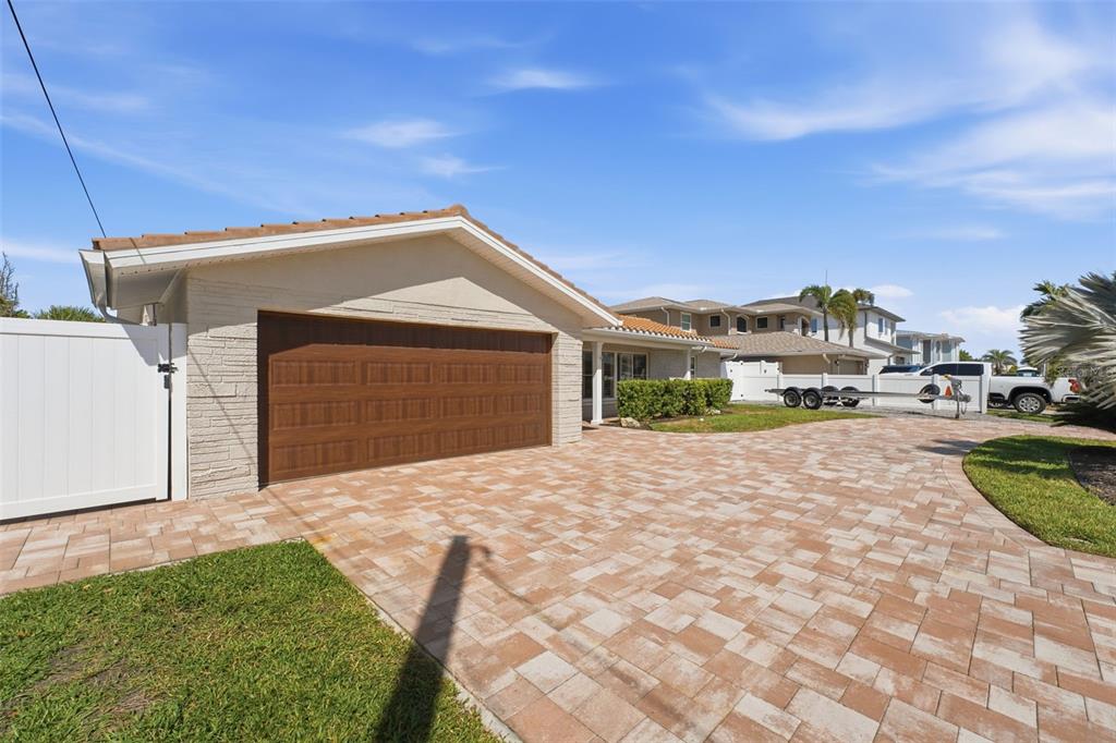 A swimming pool with lounge chairs and an umbrella overlooks a canal with a boat — 6414 2ND PALM POINT, ST PETE BEACH, FL