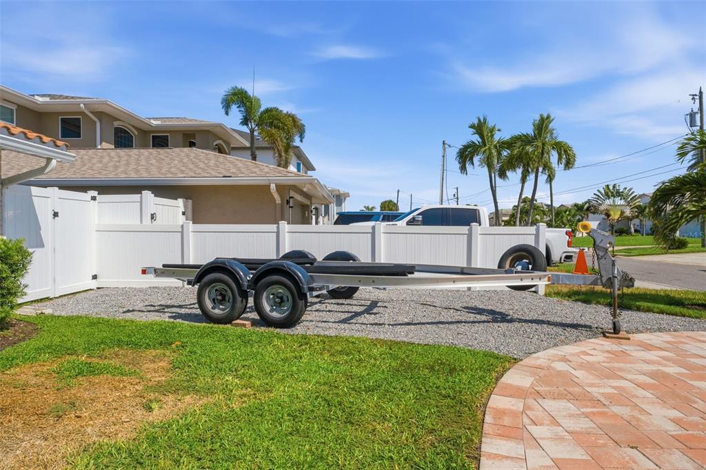 A swimming pool with lounge chairs and an umbrella overlooks a canal at sunset — 6414 2ND PALM POINT, ST PETE BEACH, FL