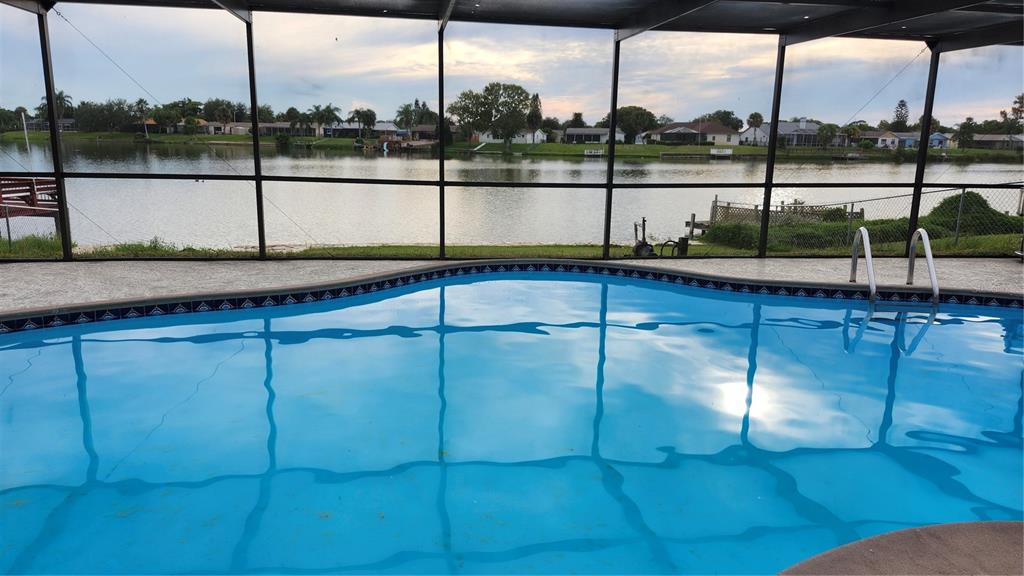 A grassy lawn overlooks a lake with two wooden docks at sunset — 9709 LAKESIDE LANE, PORT RICHEY, FL
