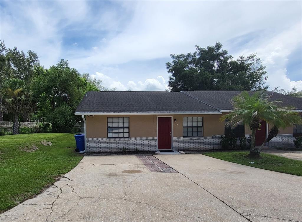 A single-story duplex with a tan exterior, brick accents, and a concrete driveway — 787 LINCOLN PARKWAY, OVIEDO, FL