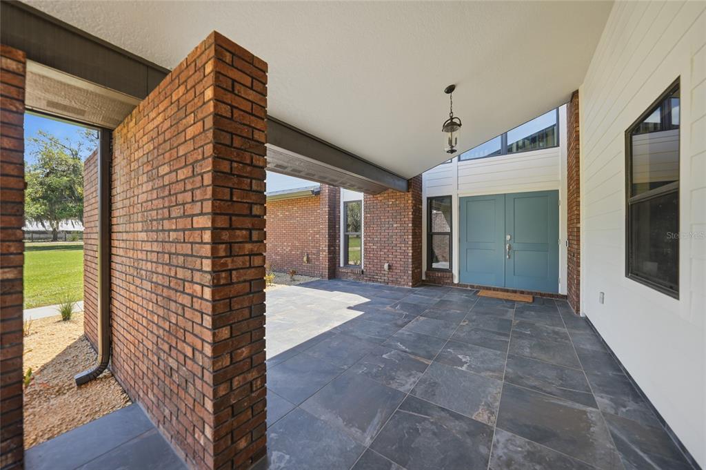 A covered entryway features a slate tile floor, brick walls, and double blue front doors — 3049 SW COUNTY ROAD 769, ARCADIA, FL