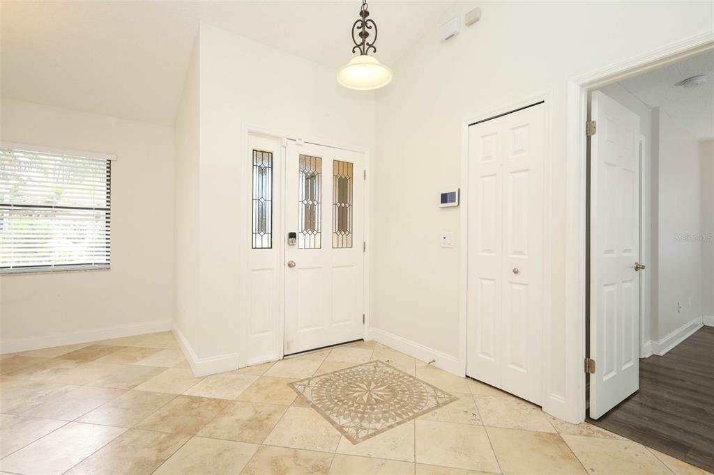 An entryway features a white front door with glass panels, tile flooring, and a closet — 9110 PALM TREE DRIVE, WINDERMERE, FL