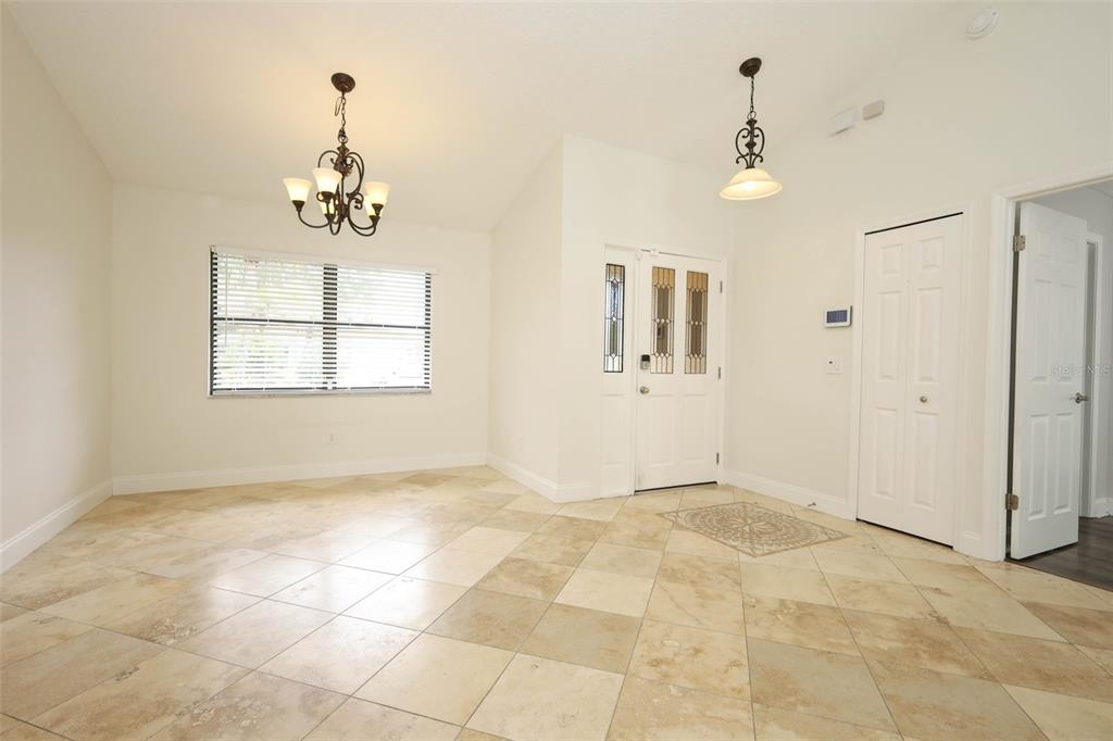 A bright entryway with light-colored tile flooring, a chandelier, and a white front door — 9110 PALM TREE DRIVE, WINDERMERE, FL