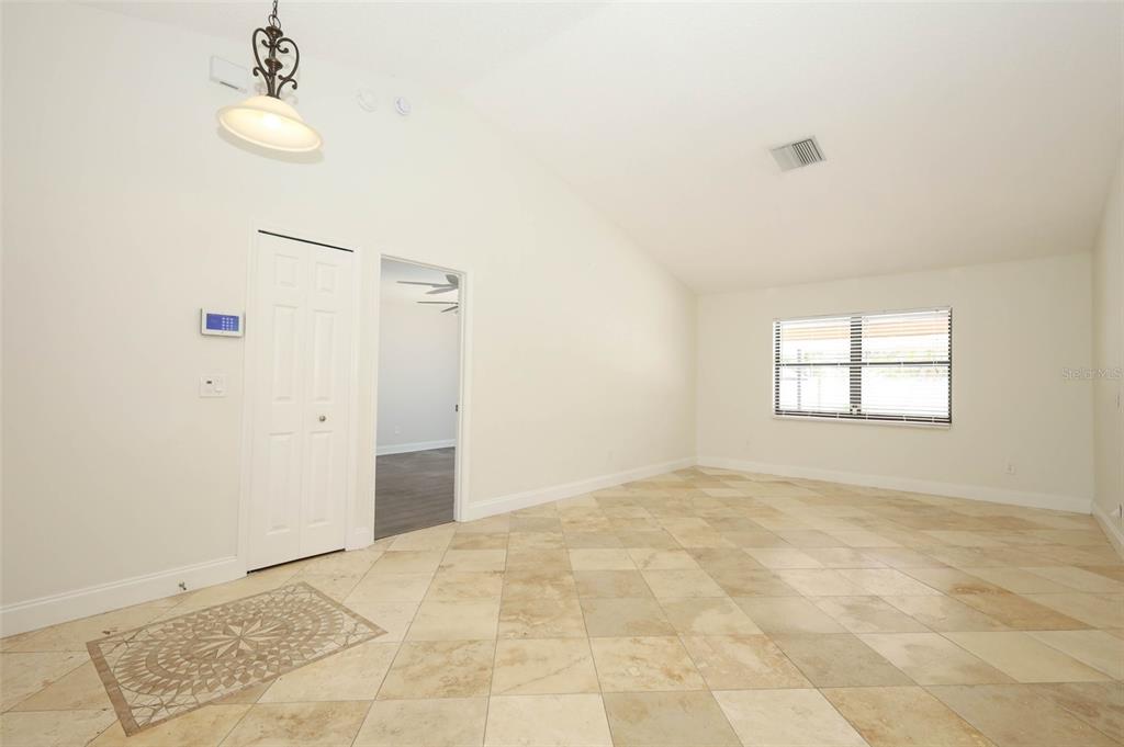 An empty room with vaulted ceilings, tile flooring, a window, and a doorway — 9110 PALM TREE DRIVE, WINDERMERE, FL