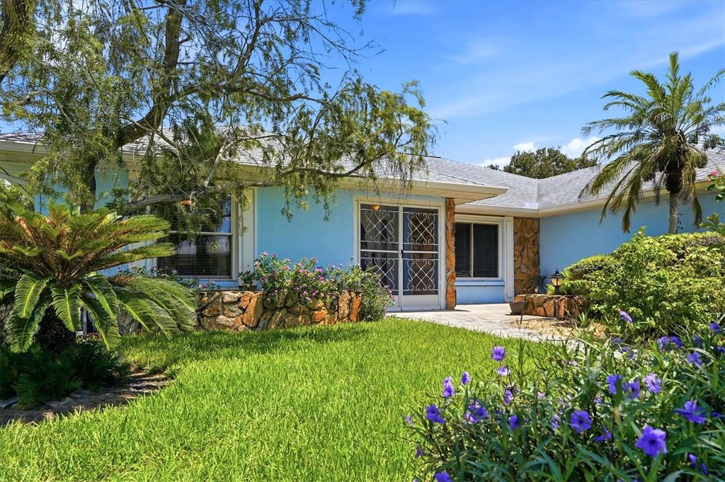 A light blue house with a stone planter, a screen door, and a palm tree — 5015 86TH STREET COURT W, BRADENTON, FL