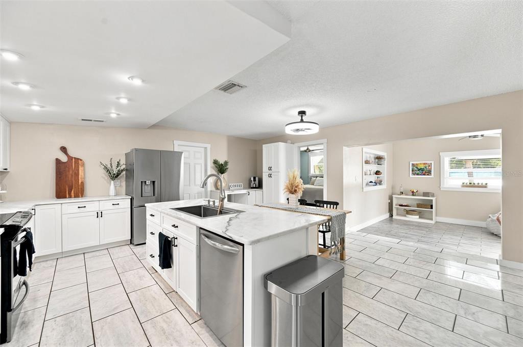 A living room features a dark blue sectional sofa, a bay window, and hardwood floors — 6230 CEDAR STREET NE, ST PETERSBURG, FL