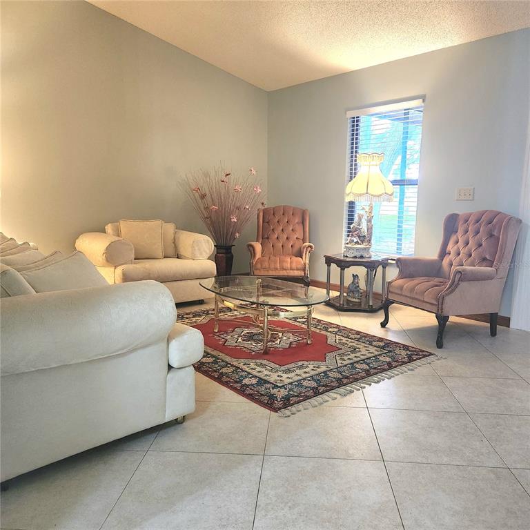 A living room features tile floors, a patterned area rug, and several upholstered chairs — 2805 LAKE TOHOPEKALIGA BOULEVARD, KISSIMMEE, FL