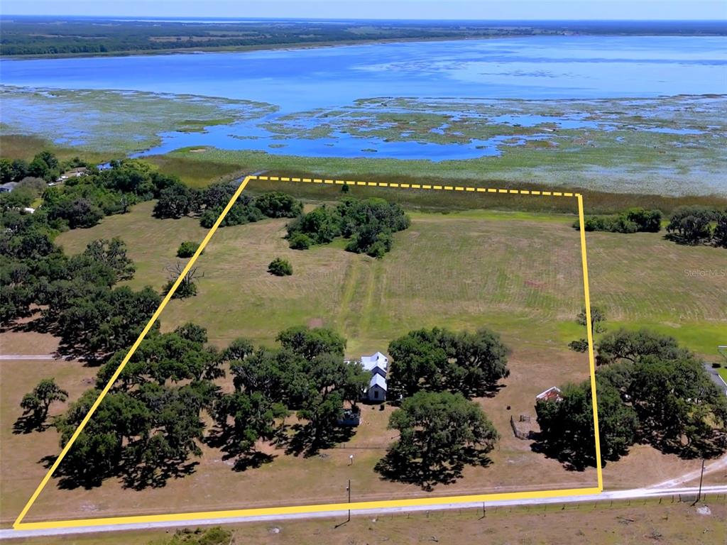 An aerial view shows a rural property with a house, trees, and lakefront access — 3650 LAKE TOHOPEKALIGA ROAD, ST CLOUD, FL