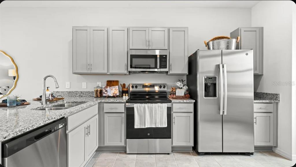A kitchen features light gray cabinets, granite countertops, and stainless steel appliances — 675 NESS ISLAND DRIVE UNIT 0, MOUNT DORA, FL