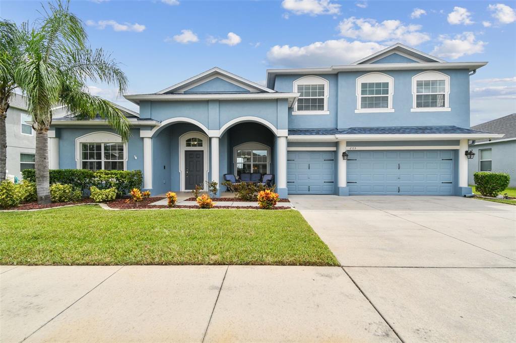 A two-story blue house with a three-car garage and a covered front entryway — 205 ORANGE MILL AVE, RUSKIN, FL