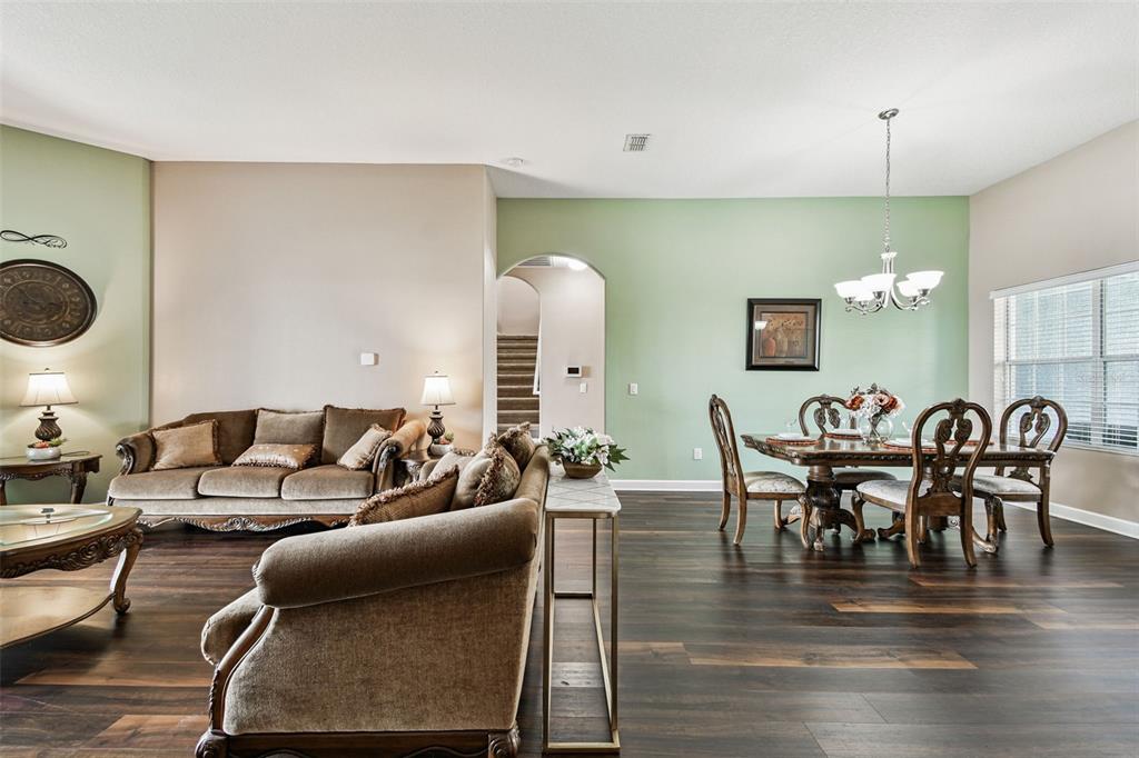 A living and dining room area features dark wood flooring, green accent walls, and traditional furniture — 205 ORANGE MILL AVE, RUSKIN, FL