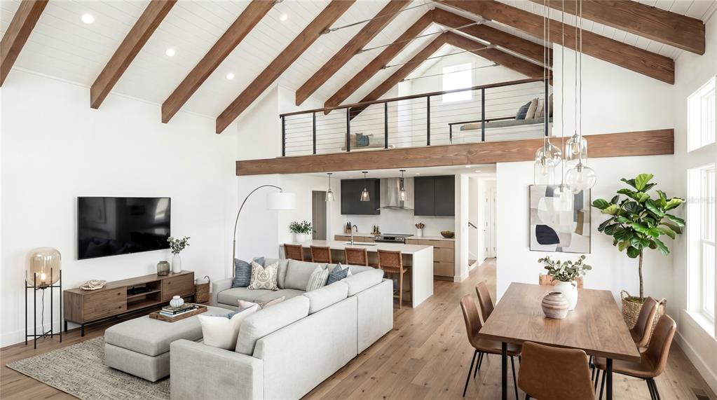 An open-concept living and dining area features vaulted ceilings with exposed wooden beams — 311 59TH STREET UNIT B, HOLMES BEACH, FL