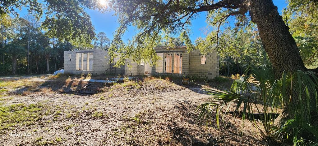 An exterior view of a single-story concrete block house under construction in a wooded area — 680 E BLACK POINT ROAD, BUNNELL, FL