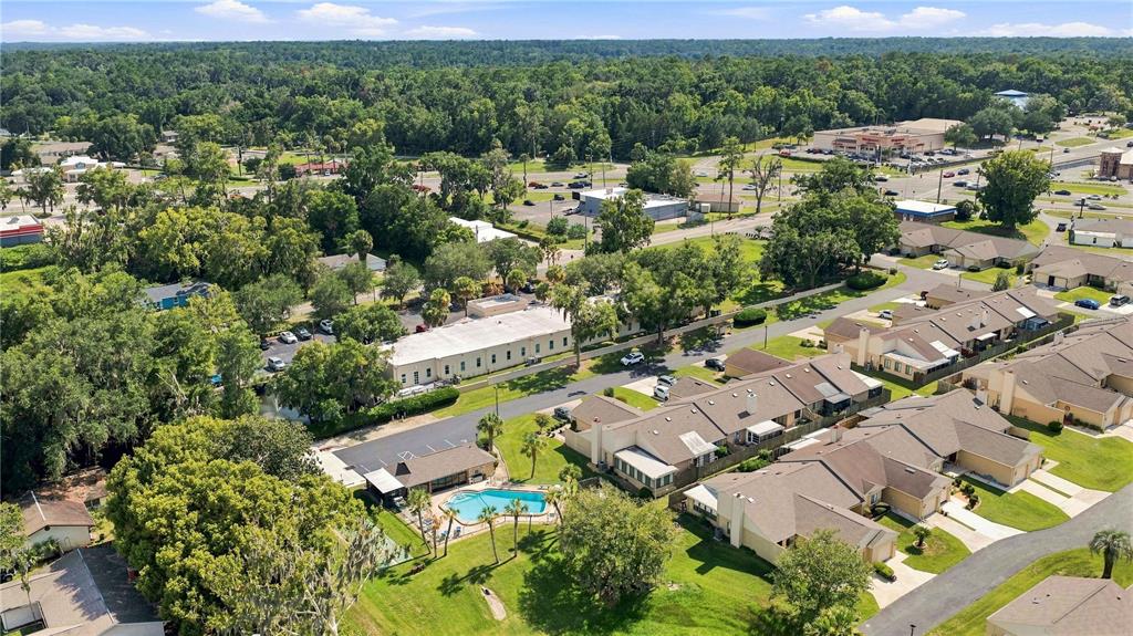 An aerial view shows a residential complex with a swimming pool and surrounding wooded areas — 5033 SE 109TH PLACE, BELLEVIEW, FL
