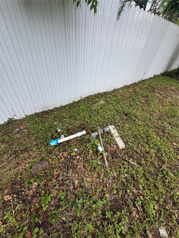 Exposed irrigation pipes and wiring sit on the ground next to a white metal fence — 2211 KEUKA AVENUE, LEESBURG, FL