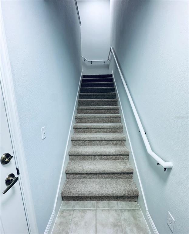 A staircase with gray carpet leads upward between two light blue walls — 233 SOUTHERN PECAN CIRCLE UNIT 101, WINTER GARDEN, FL