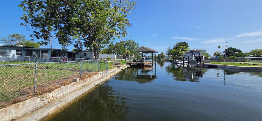 A canal view showing a fenced yard, a boat lift, and a docked motorboat — 13324 CAROL DRIVE, HUDSON, FL