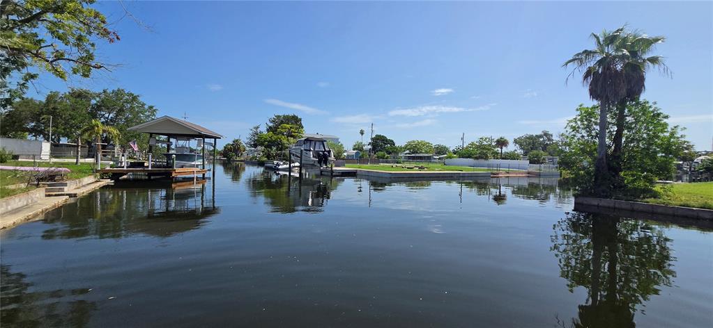 A canal view featuring a boat lift, a docked boat, and surrounding residential waterfront properties — 13324 CAROL DRIVE, HUDSON, FL