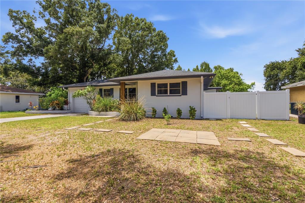 A single-story house with a white exterior, a garage, and a white vinyl privacy fence — 10 S ORION AVENUE, CLEARWATER, FL