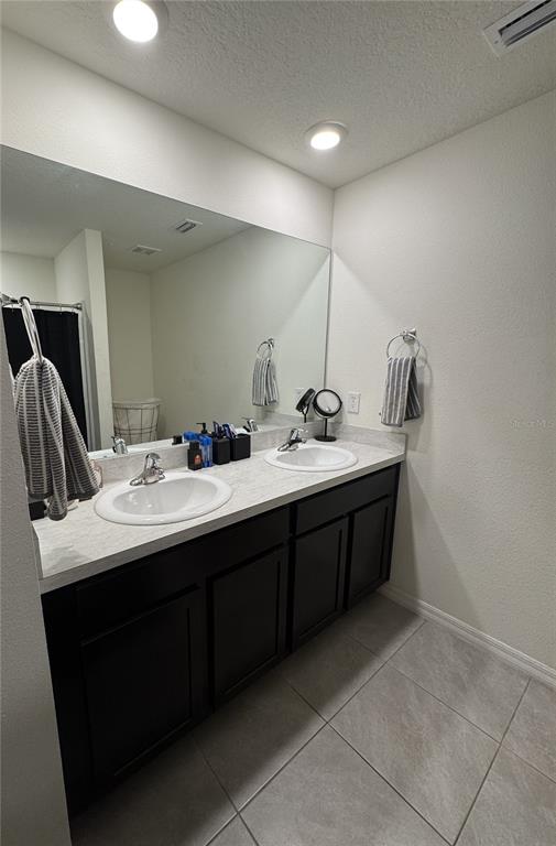 A bathroom features a double vanity with dark cabinets, white countertops, and a large mirror — 4234 AUTUMN FOG COURT, PALMETTO, FL