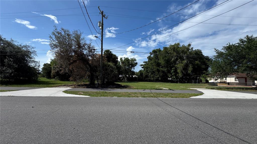A vacant, grassy residential lot sits between two paved driveways under a blue sky — 41 E MICHAEL GLADDEN BOULEVARD, APOPKA, FL