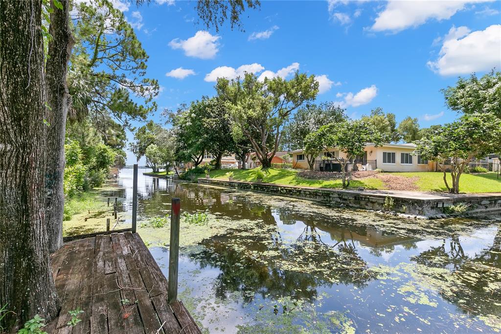 A wooden dock overlooks a canal leading to a lake beside a single-story house — 1435 WEGMANN DRIVE, TARPON SPRINGS, FL