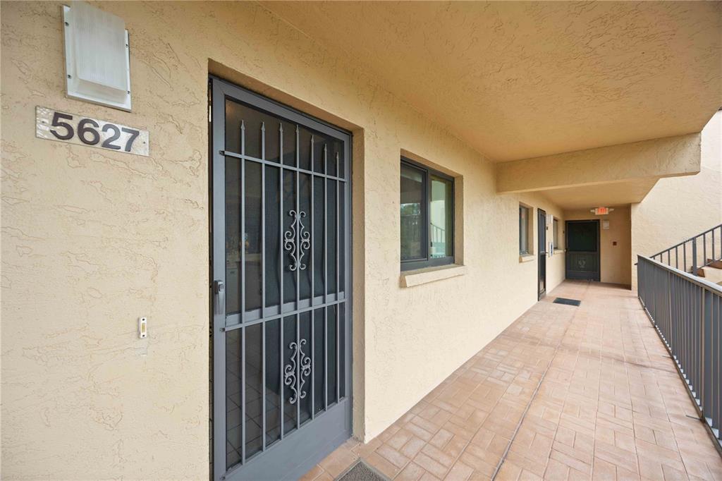 An exterior walkway features a metal security door, a window, and a tiled floor — 5627 ASHTON WAY UNIT 5627, SARASOTA, FL