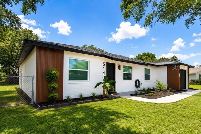 A white single-story house features dark wood siding accents, a black roof, and a chain-link fence — 5140 TREND ROAD, WEST MELBOURNE, FL