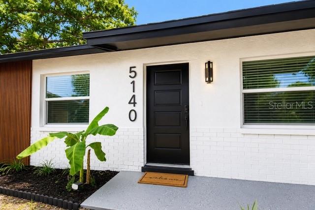 The exterior of a white house features a black front door, vertical address numbers, and windows — 5140 TREND ROAD, WEST MELBOURNE, FL