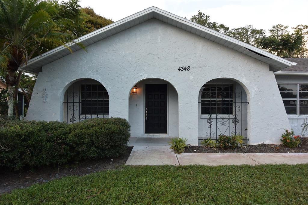 A single-story house features a light-colored stucco exterior with three arched openings and security bars — 4348 BLACK FOX DRIVE, NEW PORT RICHEY, FL