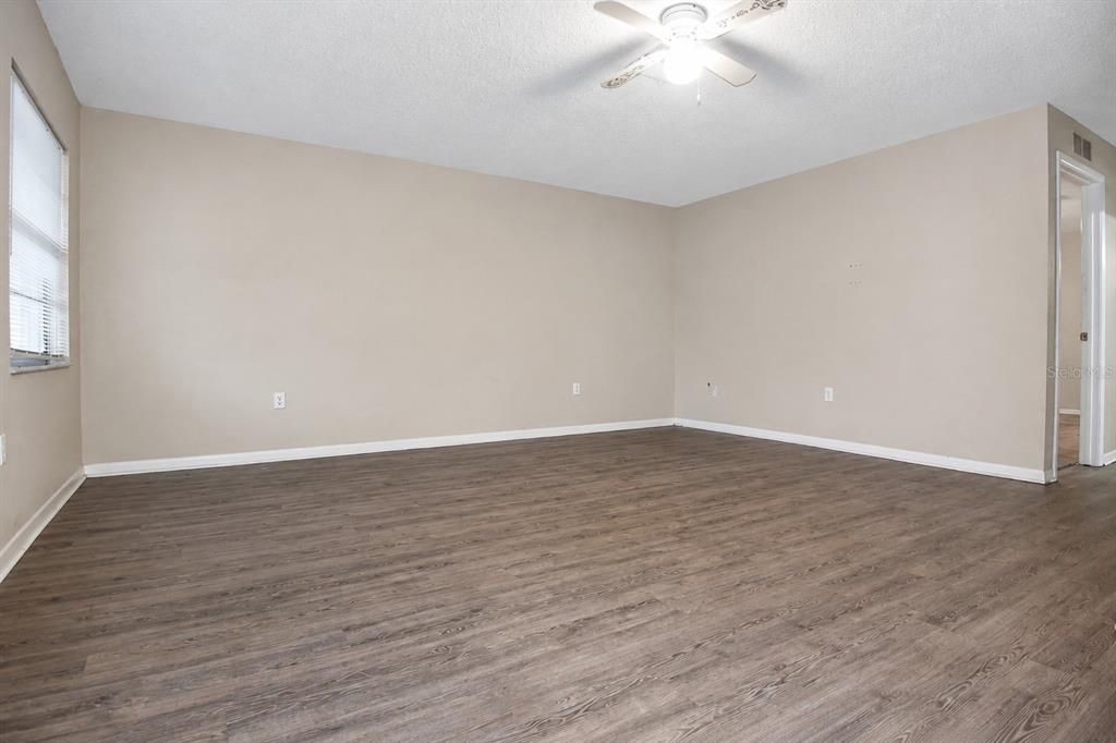 An empty room with light-colored walls, wood-look flooring, and a ceiling fan — 4348 BLACK FOX DRIVE, NEW PORT RICHEY, FL