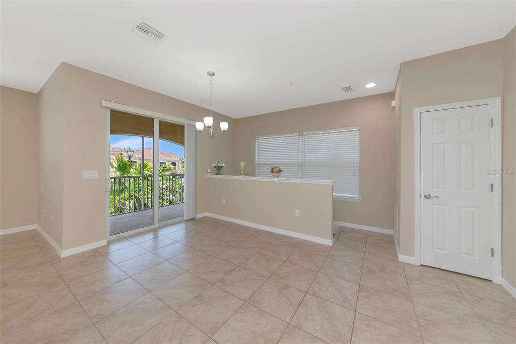 A dining area with tile flooring, a chandelier, a half-wall, and a sliding glass door — 4296 EXPEDITION WAY UNIT 104, OSPREY, FL
