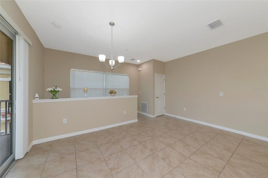 A dining area with tile flooring, a chandelier, and a half-wall overlooking a window — 4296 EXPEDITION WAY UNIT 104, OSPREY, FL