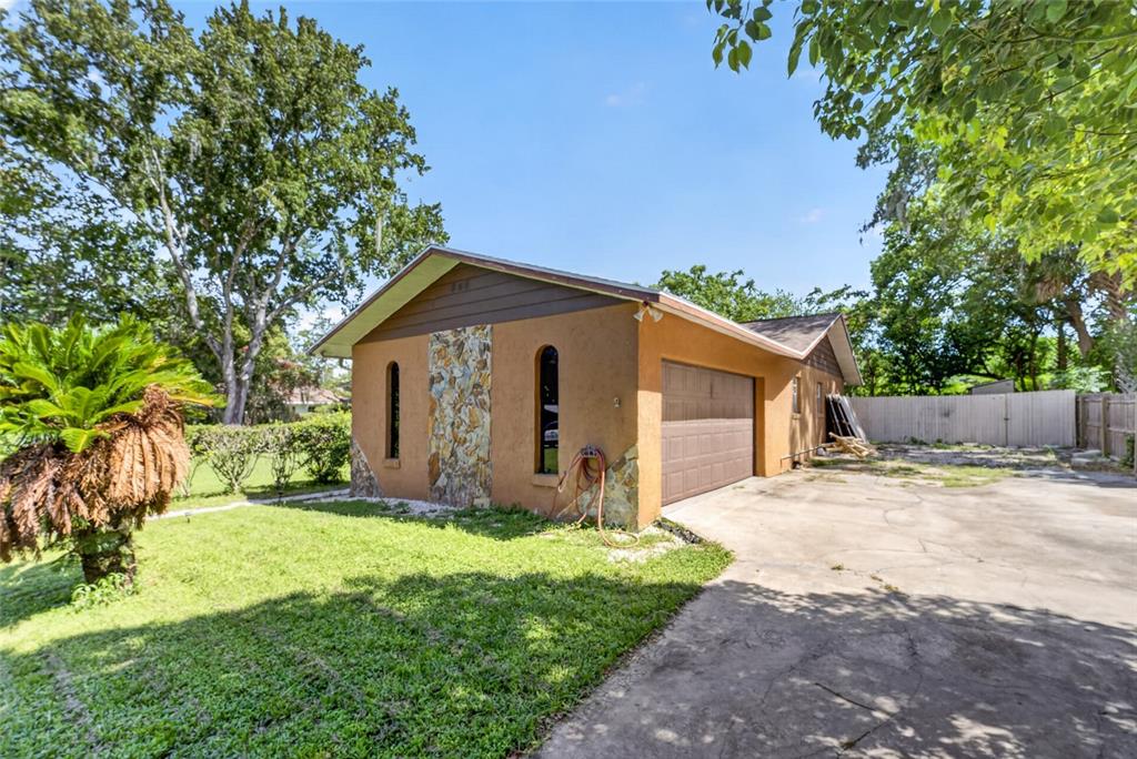 A tan house with a stone accent wall, a brown garage door, and a concrete driveway — 3216 SE 34TH STREET, OCALA, FL