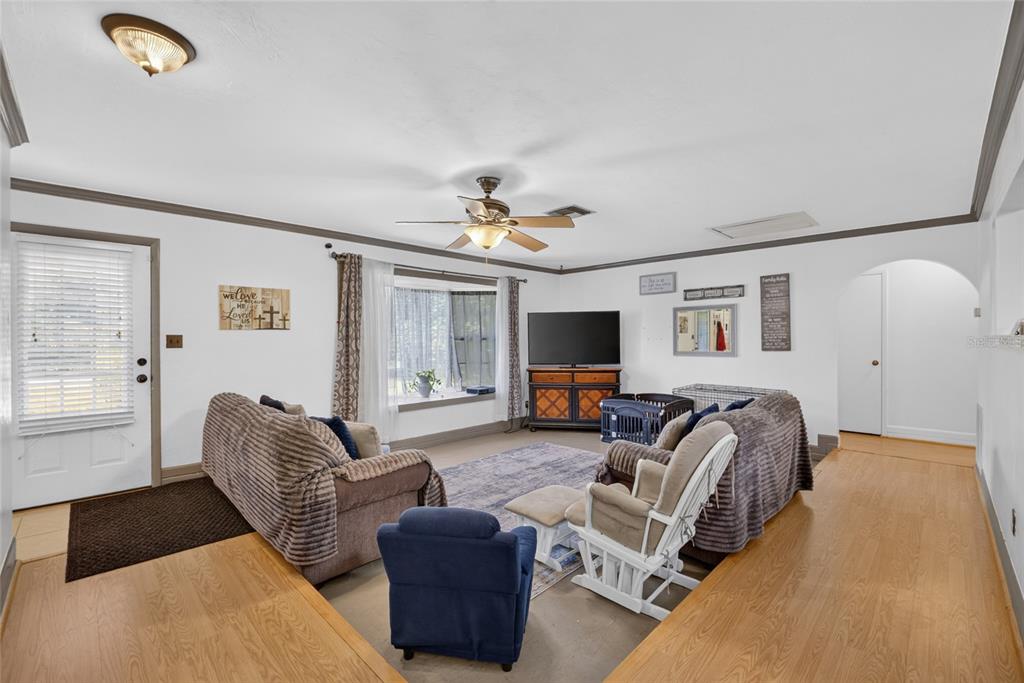A living room with a sunken carpeted area, wood flooring, a ceiling fan, and a television — 3216 SE 34TH STREET, OCALA, FL