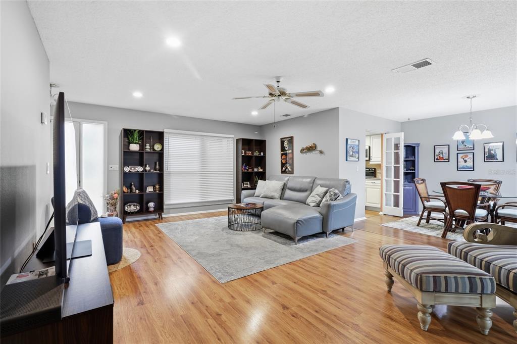 A living room with wood-look flooring, a grey sectional sofa, and an open dining area — 3191 GLEN ELYN BOULEVARD UNIT 4, SARASOTA, FL