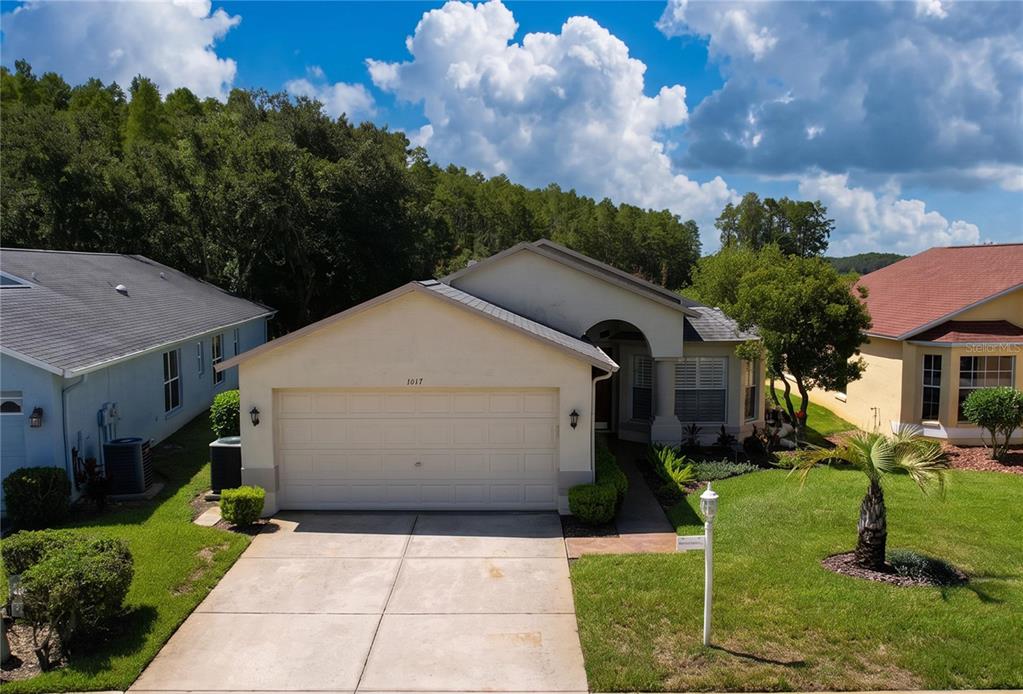 An exterior view of a single-story house with a two-car garage and a concrete driveway — 1017 SWEET JASMINE DRIVE, TRINITY, FL