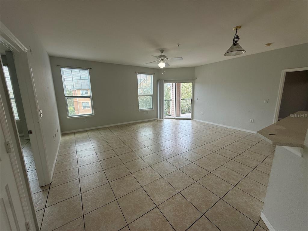 An empty living area features light-colored tile flooring, a ceiling fan, and sliding glass doors — 2000 ERVING CIRCLE UNIT 303, OCOEE, FL