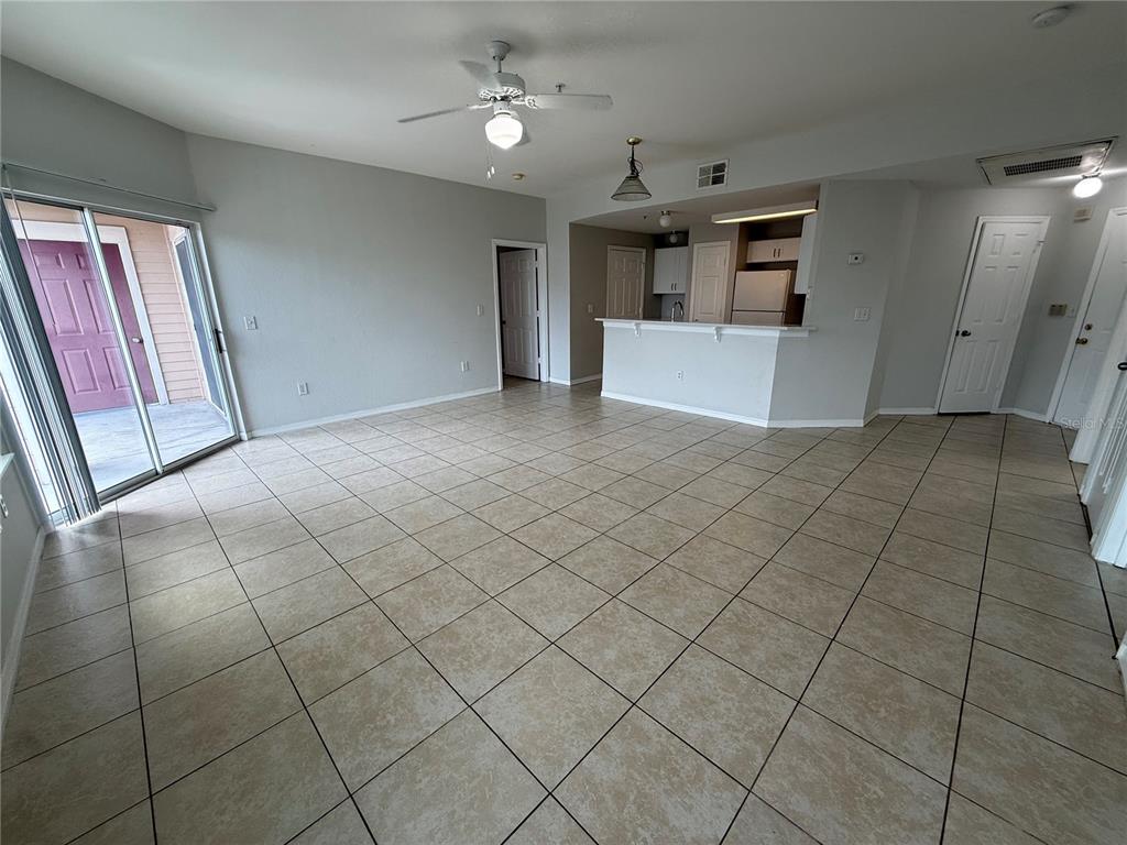 An open-concept living area features light-colored tile flooring, a ceiling fan, and a kitchen island — 2000 ERVING CIRCLE UNIT 303, OCOEE, FL