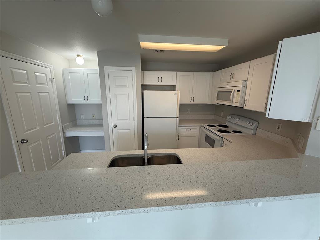 A kitchen features white cabinets, light-colored countertops, a double sink, and white appliances — 2000 ERVING CIRCLE UNIT 303, OCOEE, FL