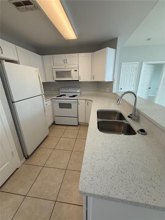 A kitchen features white cabinets, white appliances, a double sink, and speckled countertops — 2000 ERVING CIRCLE UNIT 303, OCOEE, FL