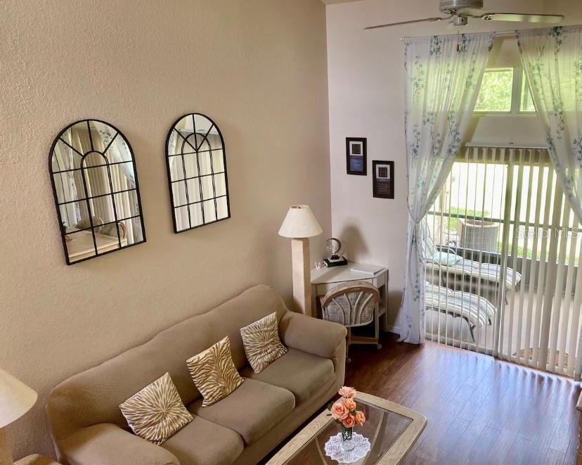 A living room with a beige sofa, two arched wall mirrors, and a sliding glass door — 3161 TAMARIND CIRCLE, KISSIMMEE, FL