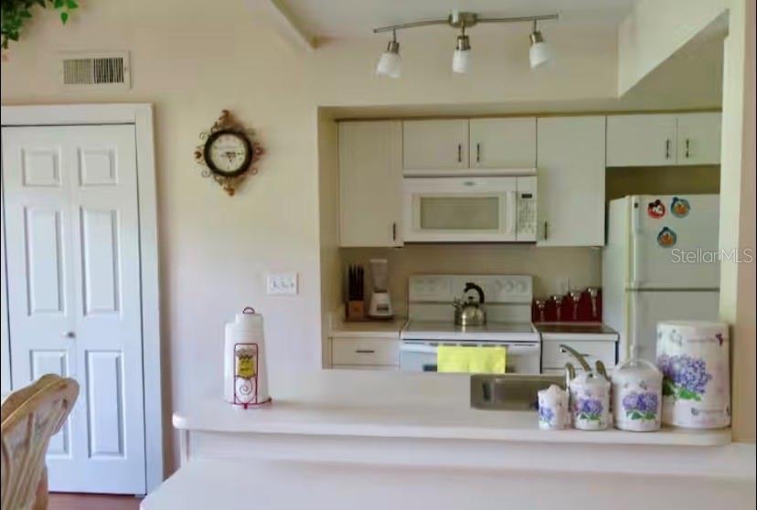 A kitchen features white cabinets, a white stove, a microwave, and a breakfast bar counter — 3161 TAMARIND CIRCLE, KISSIMMEE, FL