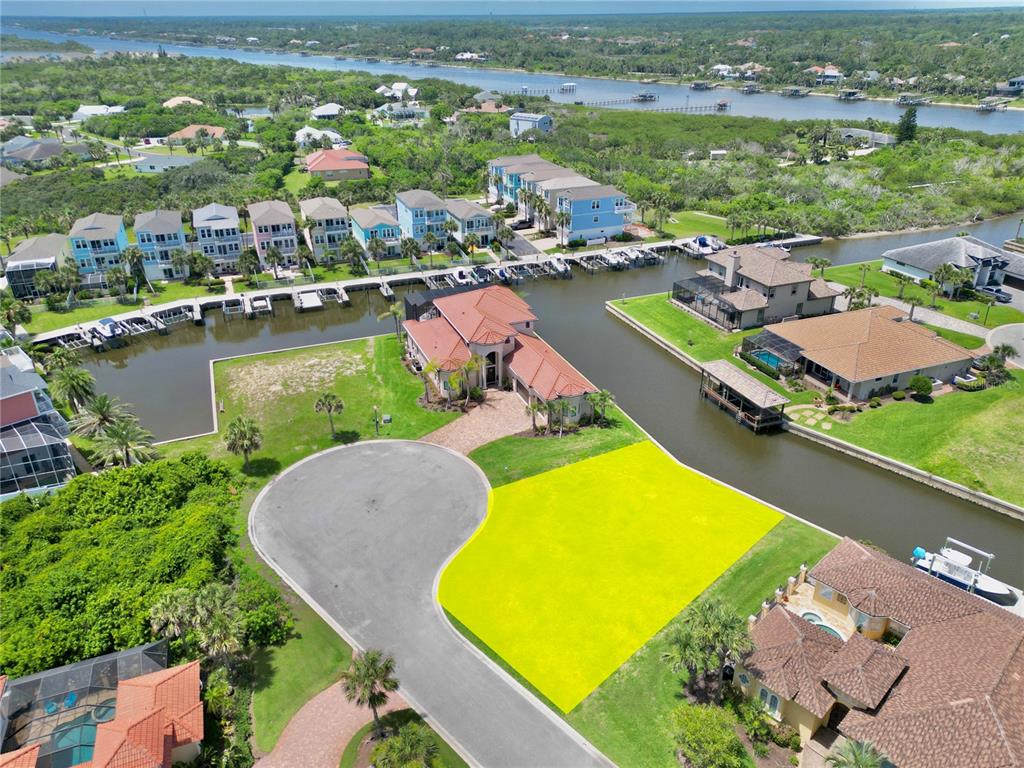 An aerial view shows a vacant, highlighted lot situated on a canal in a residential neighborhood — 90 HIDDEN COVE, BEVERLY BEACH, FL