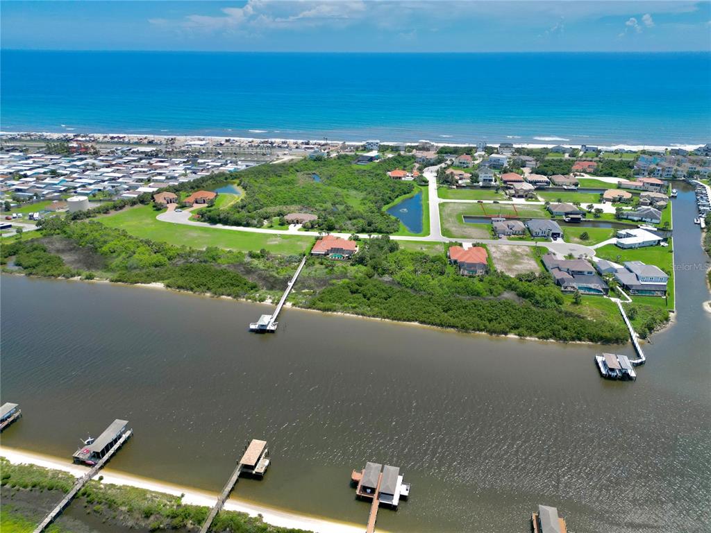 An aerial view shows waterfront homes, private docks, and a sandy beach along the ocean — 90 HIDDEN COVE, BEVERLY BEACH, FL