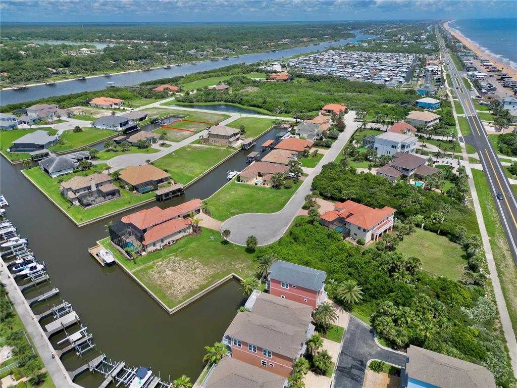 An aerial view shows waterfront homes, canals, and a road along the coast — 90 HIDDEN COVE, BEVERLY BEACH, FL
