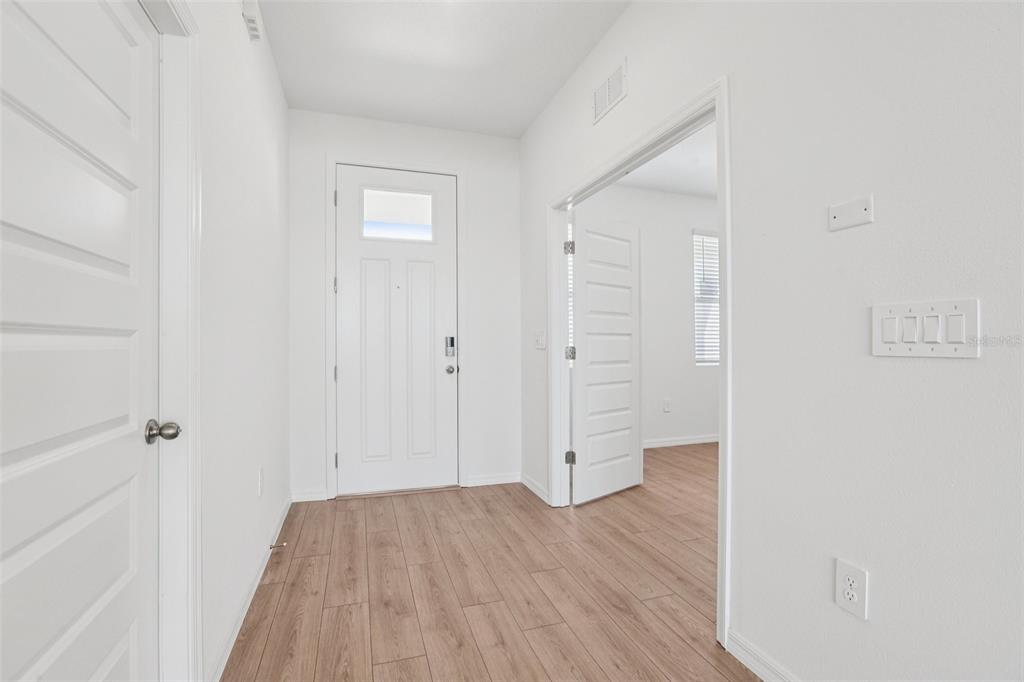 A bright entryway features light wood-look flooring, white walls, and a white front door — 5384 CLOUDBERRY AVENUE, LAKELAND, FL