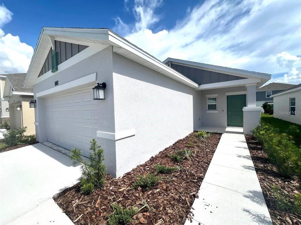 A single-story house with a white stucco exterior, a green front door, and a garage — 3978 AMBROSE AVENUE, KISSIMMEE, FL