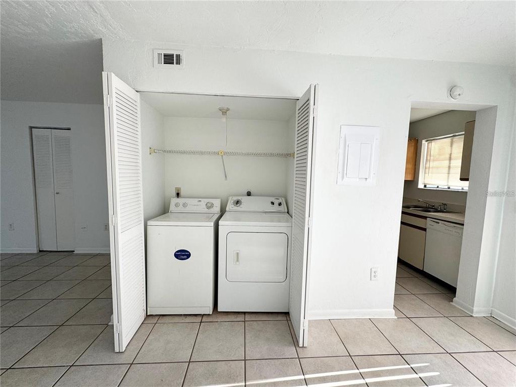A laundry closet with a washer and dryer sits between a tiled room and a kitchen — 2300 SW 43RD STREET UNIT M4, GAINESVILLE, FL