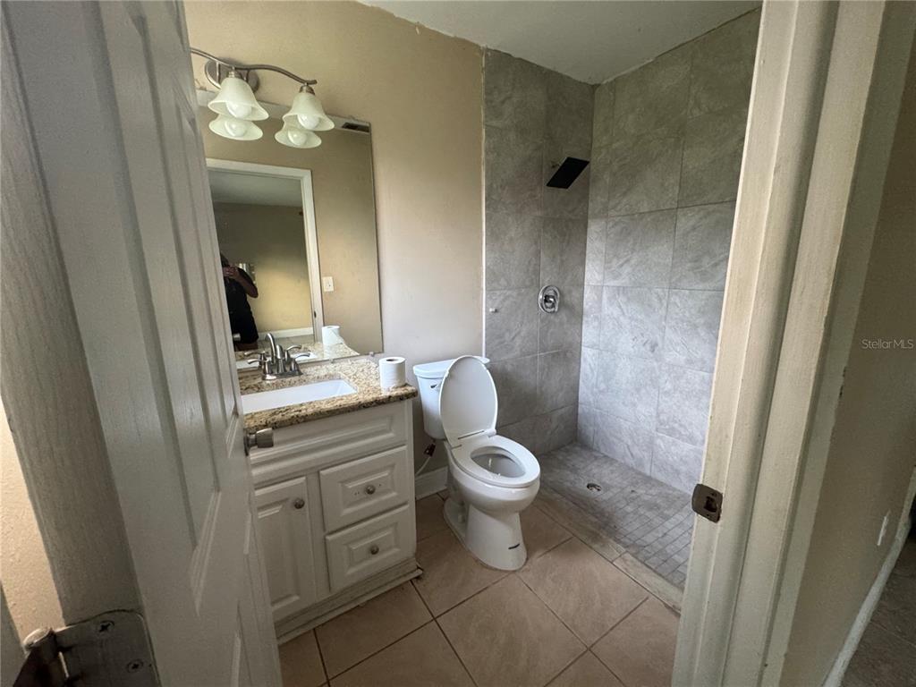 A bathroom features a vanity with a granite countertop, a toilet, and a tiled shower — 4005 CASCADE LANE, LABELLE, FL
